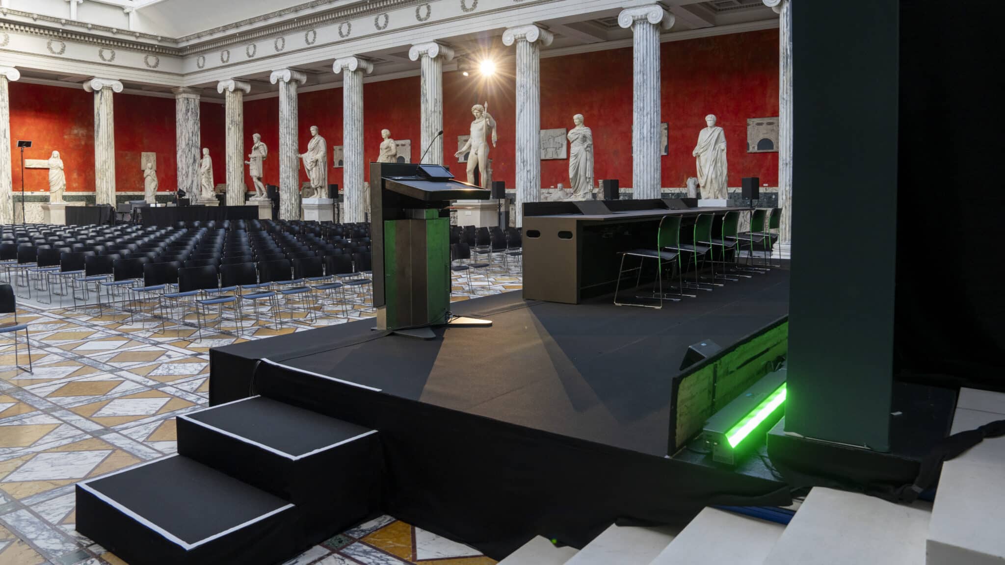 Konferencescene opsat i en stor sal med klassiske statuer